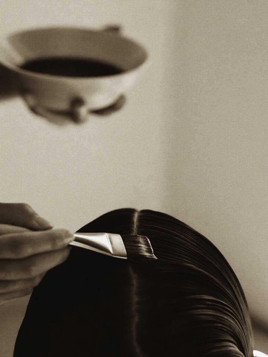 Colorist applying corrective color with a tint brush to sectioned hair