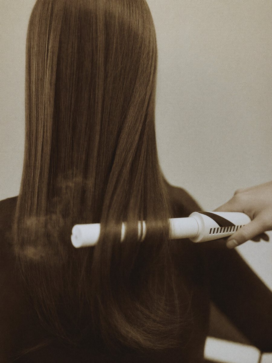 Flat iron gliding through a smooth section of hair